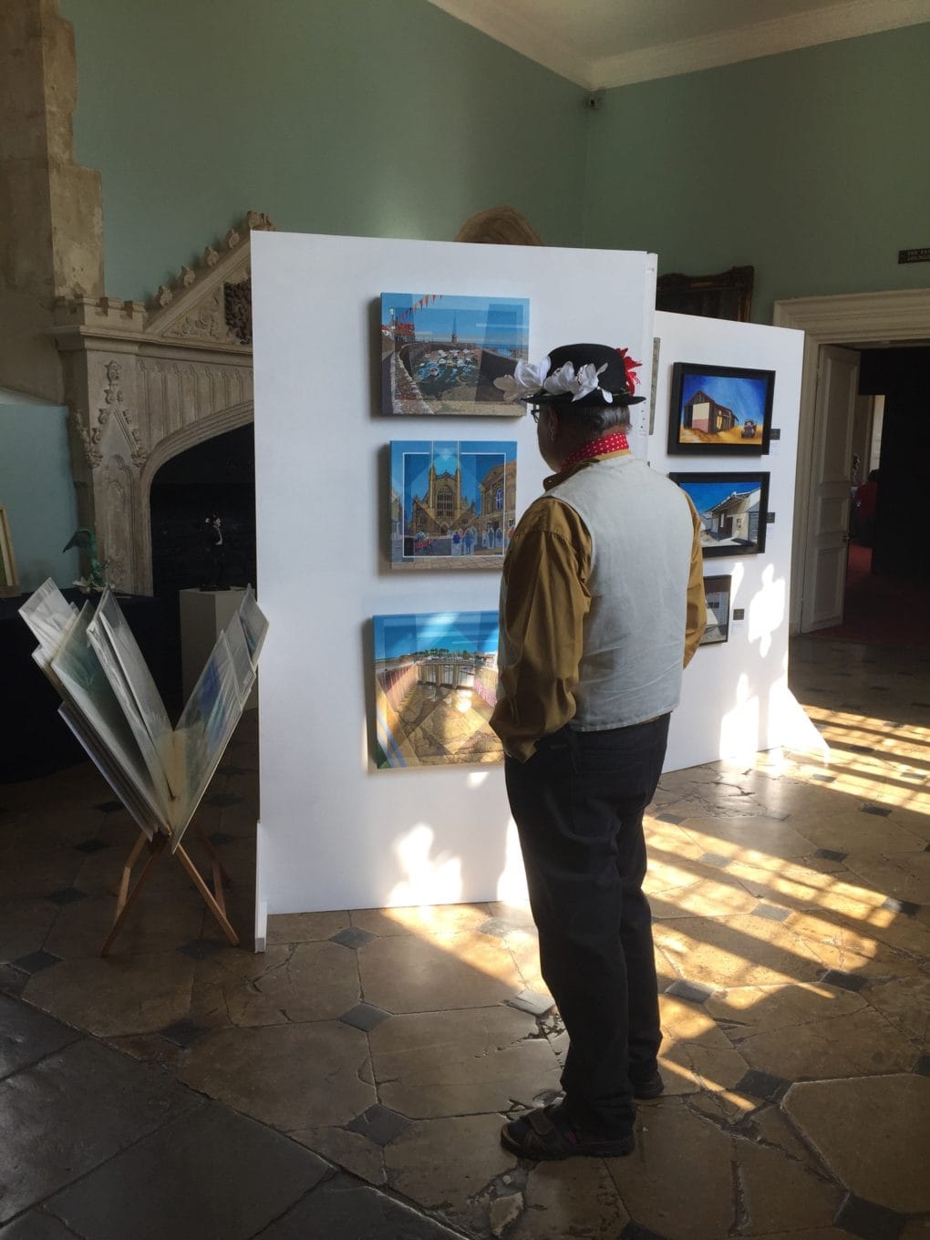 A visitor to the Great Hall Gallery wearing a festive costume looks at the artwork of Len Matthews displayed on the walls. 