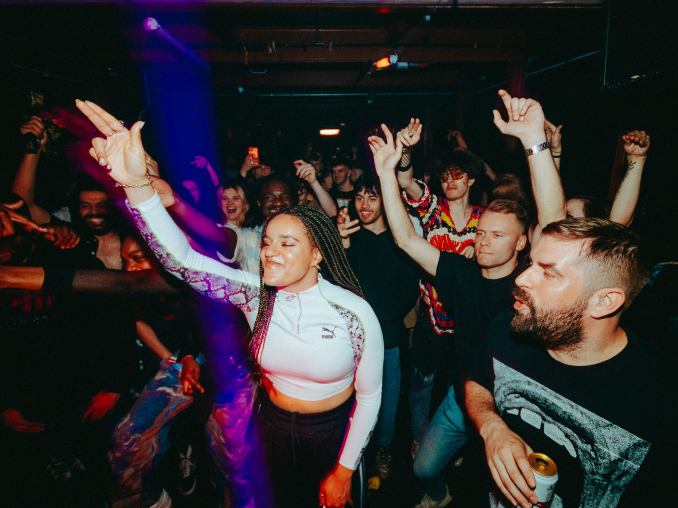 A group of people in a club with their hands in the air