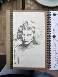 A sketchbook showing an illustration of a person's head by artist Ashley Brooks