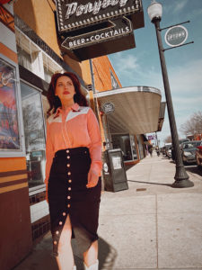 A model in retro american style clothes walks down a street