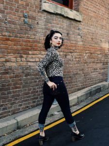 A woman in leopard print top strikes a pose in a city street