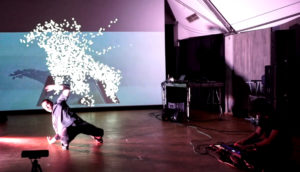 A man break dances with projected sparkles