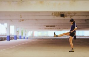 W woman stands on one foot in an empty underground car park