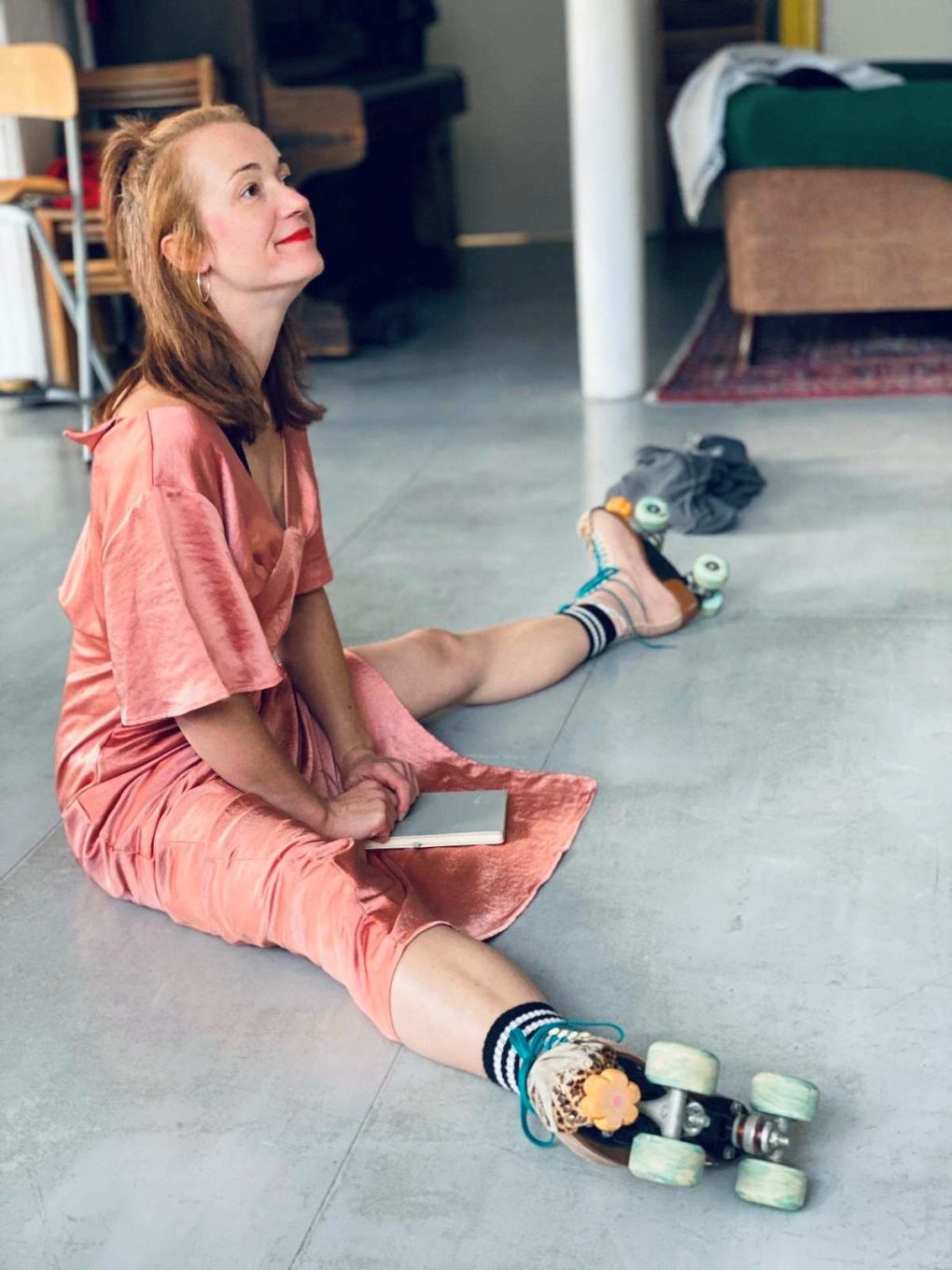 a woman wearing roller skates sits on a floor