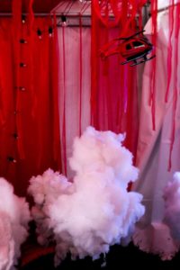 A model helicopter hangs above a cloud of smoke