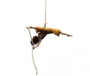A person hangs upside down from a rope in the splits
