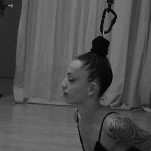 a woman lies on the floor belly down with her hair tied in a bun and attached to a rope and caribinar