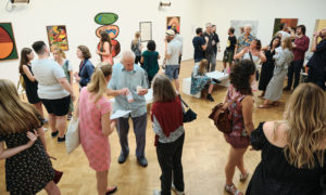 A group of people attending an exhibition opening in an art gallery
