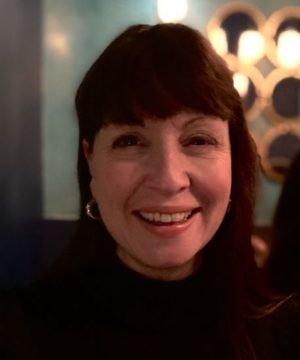 A woman with dark hair is smiling at the camera.