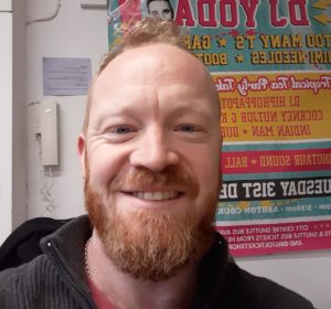 headshot of a white man with a beard smiling at the camera