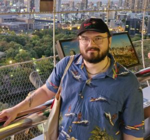A man stands by some railings overlooking a modern cityscape
